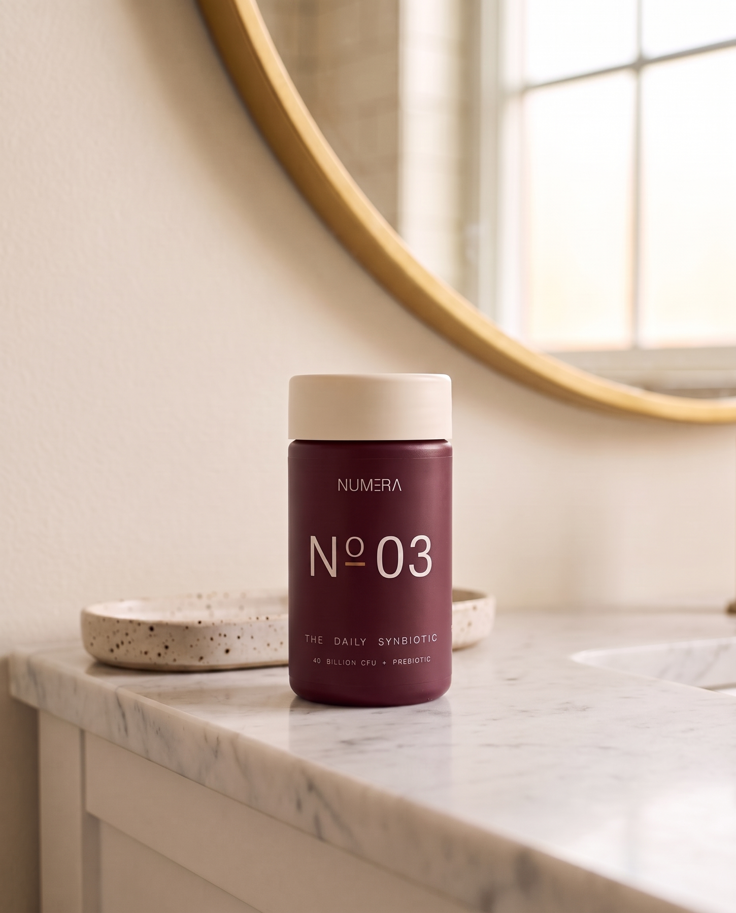 N°03 The Daily Synbiotic on a marble vanity beneath a round mirror.